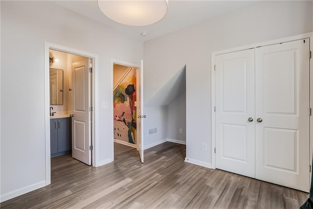 unfurnished bedroom featuring hardwood / wood-style flooring, a closet, and ensuite bathroom