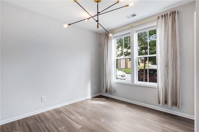 empty room with an inviting chandelier and light hardwood / wood-style flooring