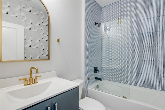 full bathroom featuring vanity, tiled shower / bath combo, and toilet