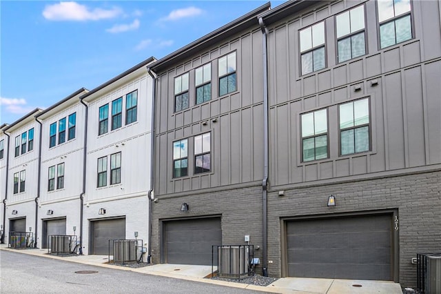 view of property exterior with a garage and central AC unit