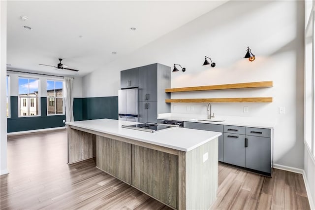 kitchen featuring gray cabinets, white fridge, a center island, light hardwood / wood-style flooring, and sink