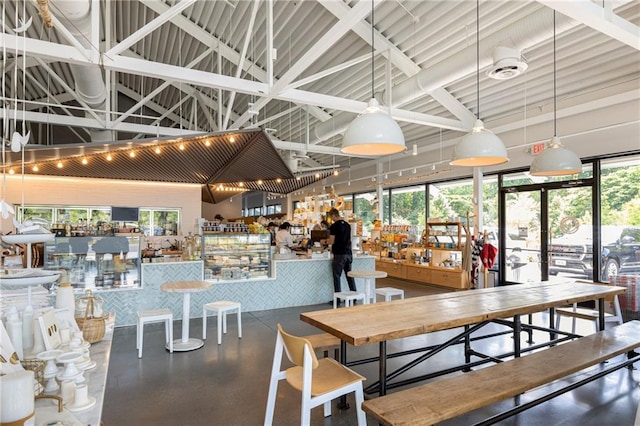 dining room with bar, concrete floors, high vaulted ceiling, and a wealth of natural light