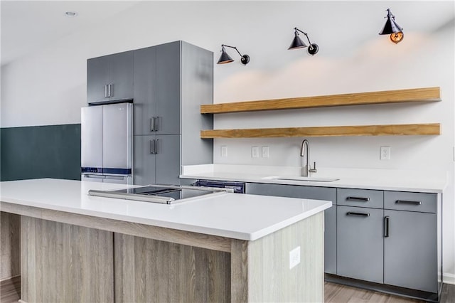 kitchen with light hardwood / wood-style floors, a center island, sink, gray cabinetry, and stainless steel appliances