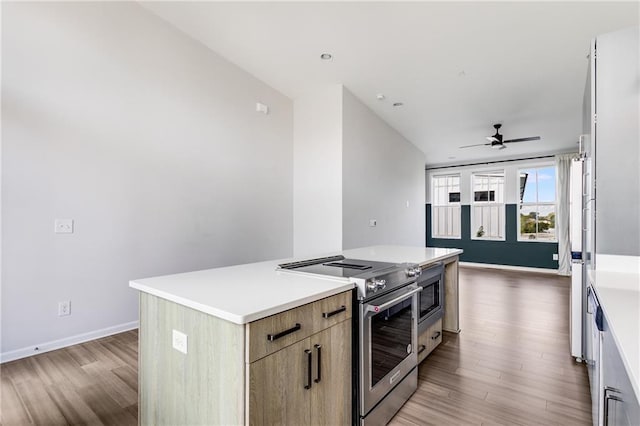 kitchen with wood-type flooring, stainless steel electric range oven, ceiling fan, and a center island