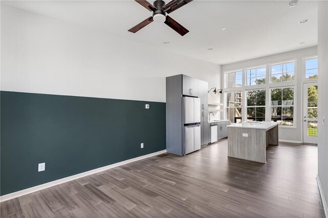 kitchen featuring ceiling fan, white refrigerator, sink, wood-type flooring, and a center island