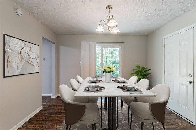 dining area featuring baseboards, a notable chandelier, dark wood finished floors, and a textured ceiling