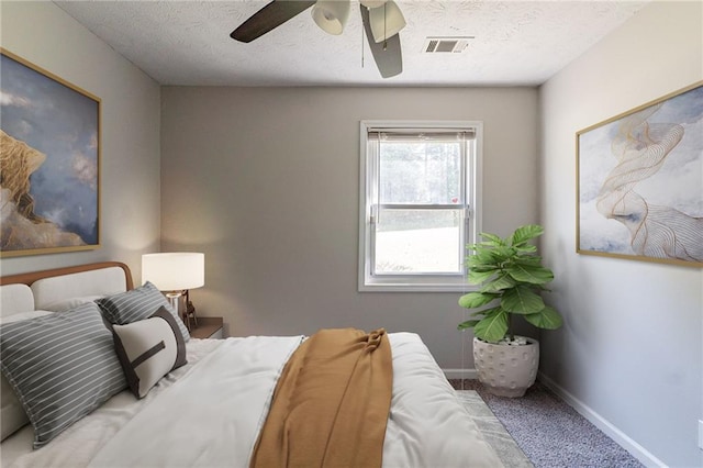bedroom with carpet, a textured ceiling, visible vents, baseboards, and ceiling fan
