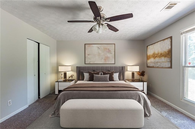 bedroom with a textured ceiling, carpet flooring, and multiple windows