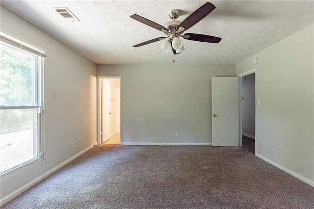 carpeted empty room with a ceiling fan, baseboards, visible vents, and a textured ceiling