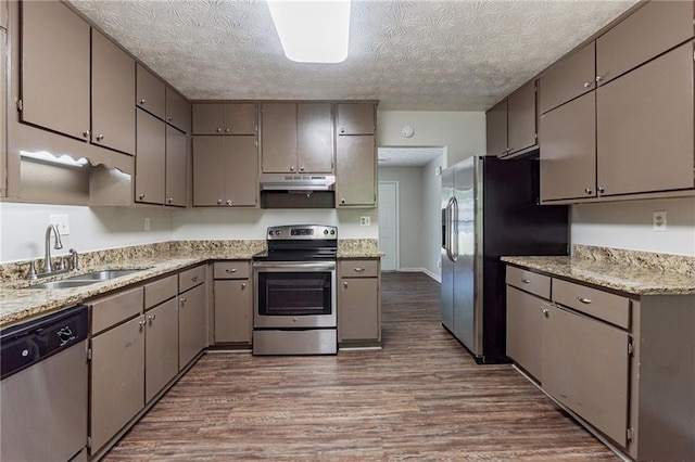 kitchen with a sink, stainless steel appliances, a textured ceiling, under cabinet range hood, and dark wood-style floors