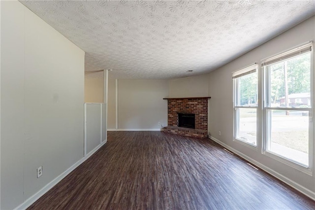 unfurnished living room featuring a fireplace, a textured ceiling, baseboards, and dark wood-style floors