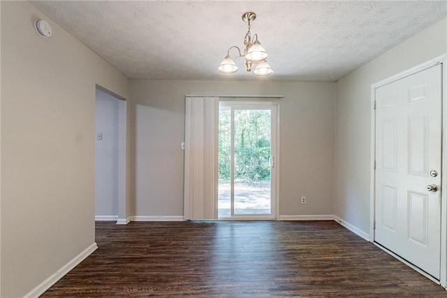 interior space featuring an inviting chandelier, a textured ceiling, and dark wood-style floors