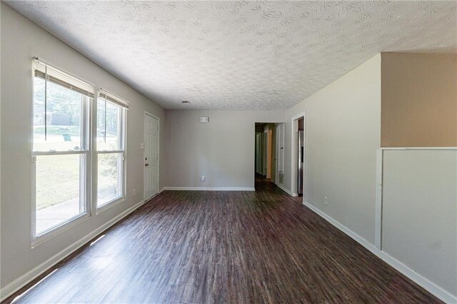 spare room with baseboards, dark wood finished floors, and a textured ceiling