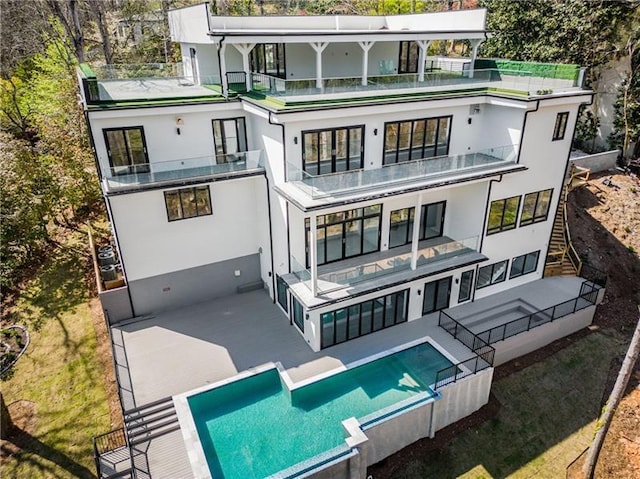 rear view of property with a balcony, a patio, and stucco siding