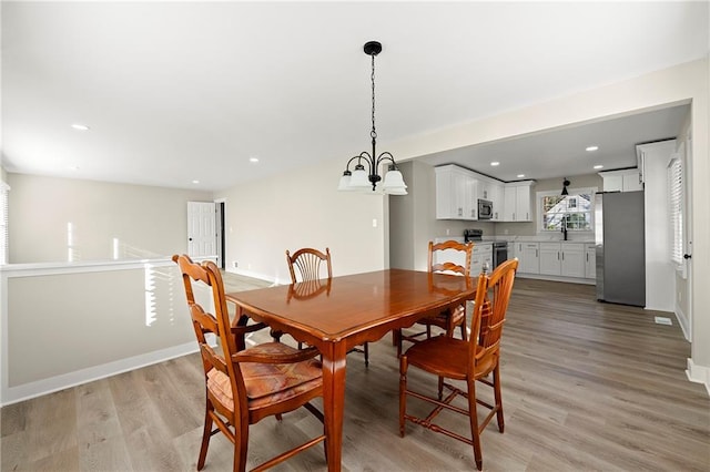 dining space featuring sink, a chandelier, and light hardwood / wood-style floors