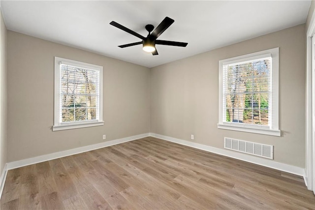 spare room featuring ceiling fan, light hardwood / wood-style flooring, and a healthy amount of sunlight