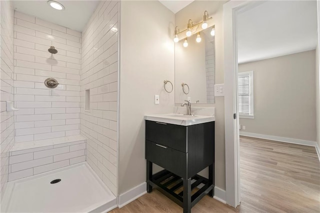 bathroom featuring wood-type flooring, a tile shower, and vanity