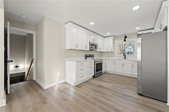 kitchen with stainless steel appliances, sink, white cabinets, and light wood-type flooring