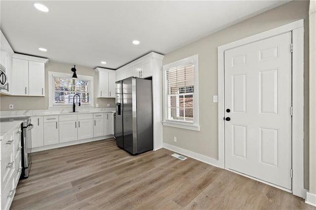 kitchen with white cabinetry, sink, light hardwood / wood-style flooring, and appliances with stainless steel finishes