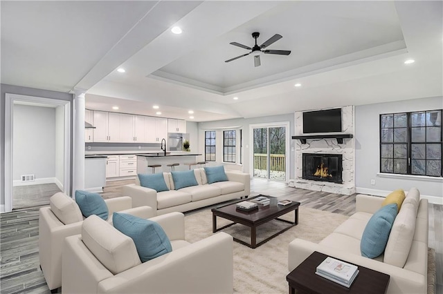 living area with baseboards, a premium fireplace, visible vents, and a raised ceiling