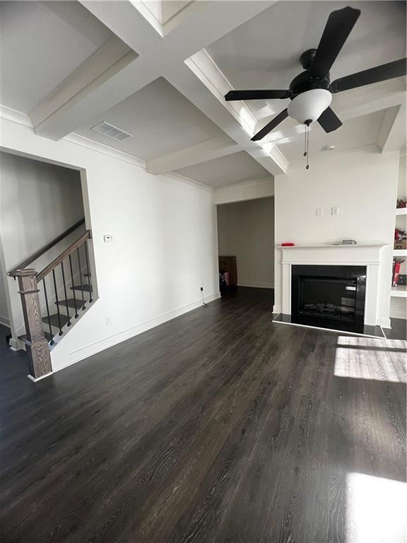 unfurnished living room featuring coffered ceiling, beam ceiling, dark hardwood / wood-style flooring, and ceiling fan