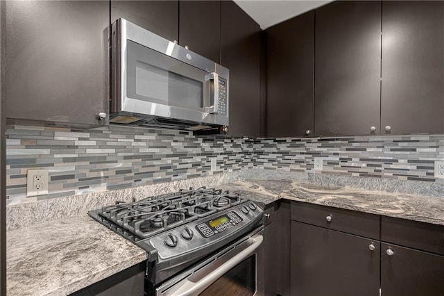 kitchen with appliances with stainless steel finishes, dark brown cabinets, stone counters, and tasteful backsplash