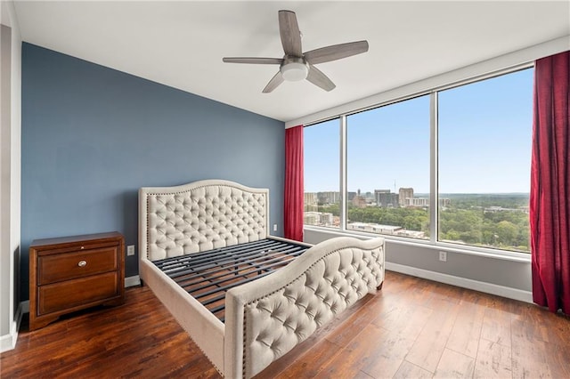 bedroom featuring ceiling fan, dark hardwood / wood-style floors, and multiple windows