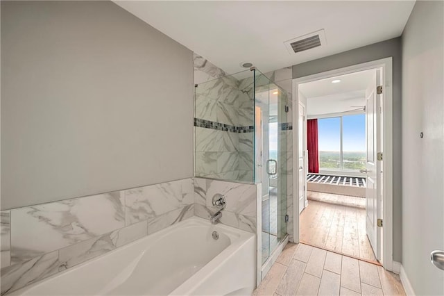 bathroom with hardwood / wood-style flooring and independent shower and bath