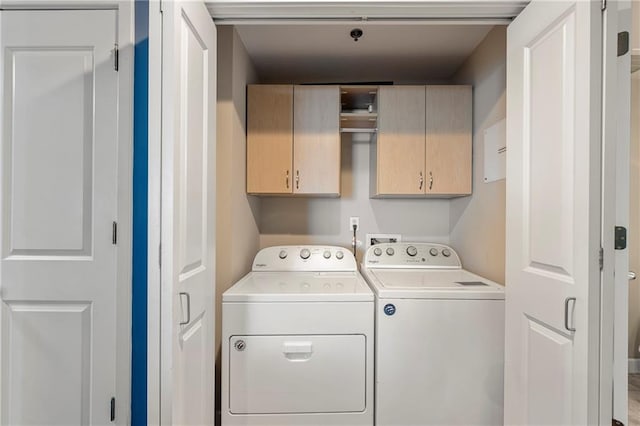 clothes washing area with washing machine and clothes dryer and cabinets