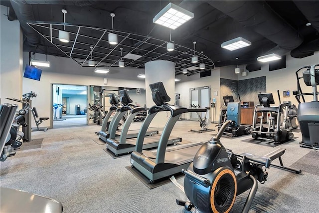 exercise room with carpet floors and a towering ceiling