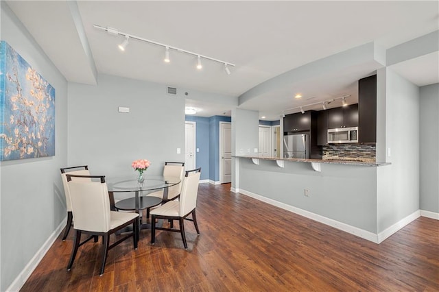 dining area featuring track lighting and dark hardwood / wood-style floors