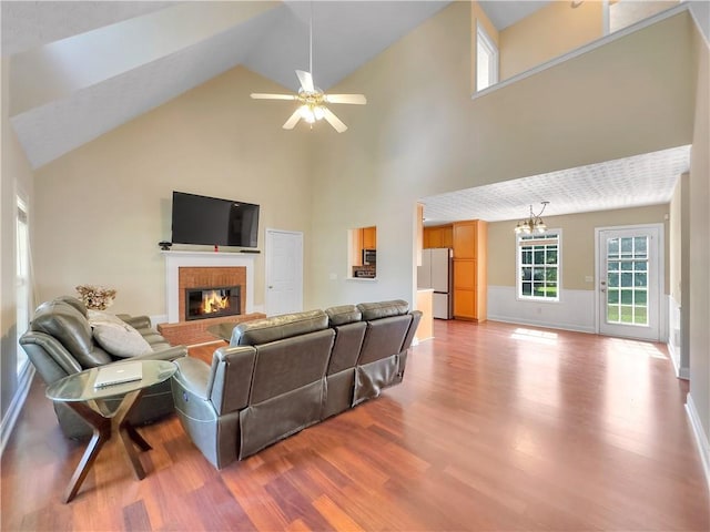 1012 Gloria Grand Blvd, Mcdonough, GA 30252 - living area featuring ceiling fan, wood finished floors, high vaulted ceiling, a brick fireplace, and a chandelier