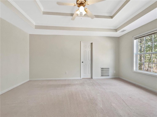 unfurnished room featuring a tray ceiling, baseboards, visible vents, and ornamental molding