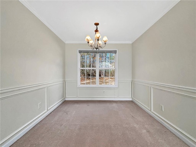 unfurnished dining area featuring crown molding, carpet flooring, wainscoting, and a chandelier