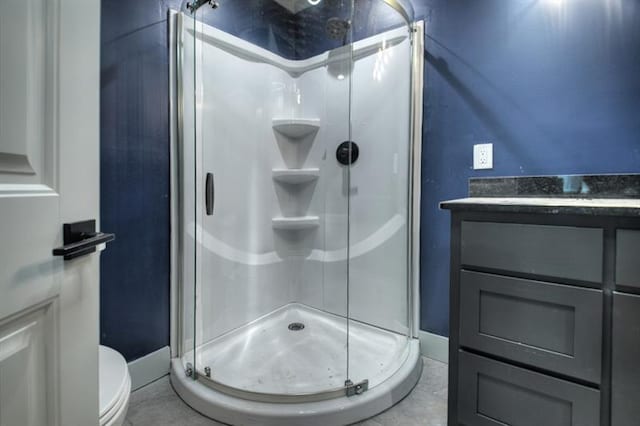 bathroom featuring toilet, vanity, and a shower with shower door