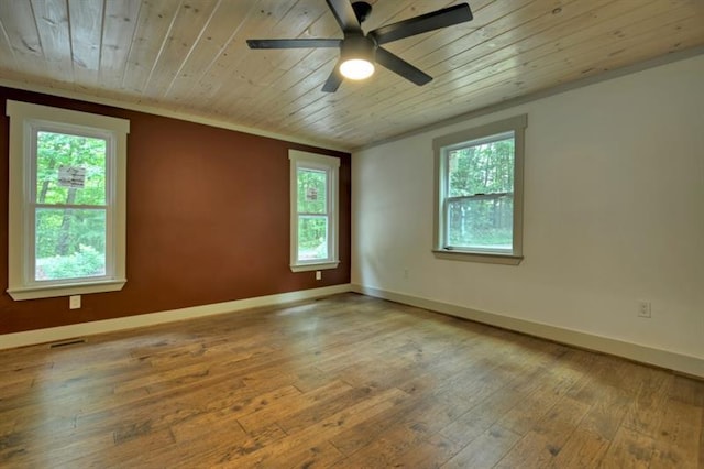 empty room with wood-type flooring, a wealth of natural light, ceiling fan, and crown molding