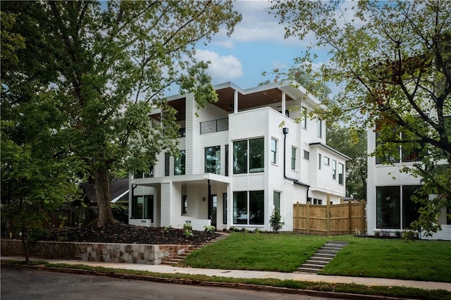 contemporary house with a balcony and a front lawn