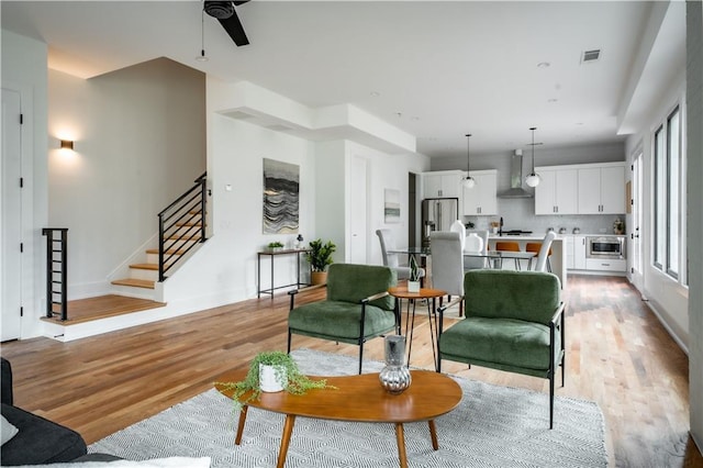 living room with ceiling fan, light wood-type flooring, and sink