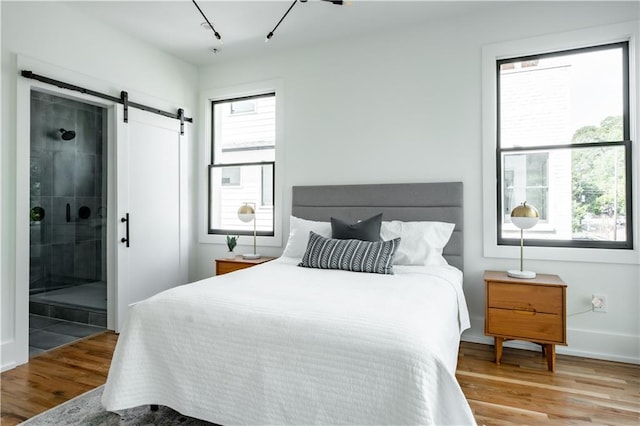 bedroom featuring light hardwood / wood-style flooring, a barn door, and ensuite bathroom