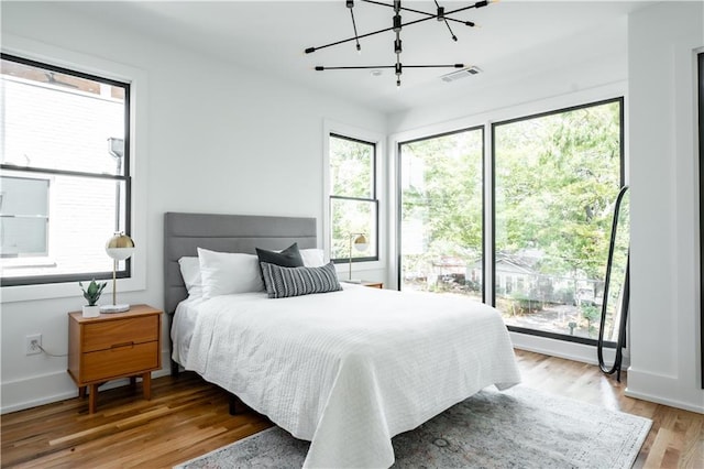 bedroom featuring light hardwood / wood-style floors, multiple windows, and a chandelier