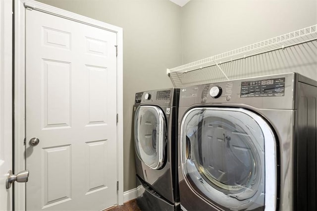 clothes washing area with laundry area, baseboards, and separate washer and dryer