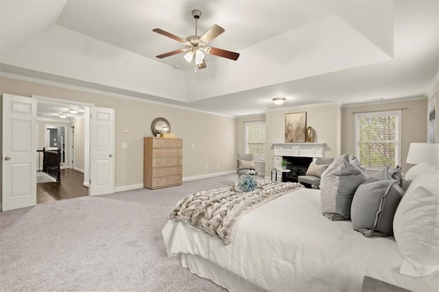 bedroom with baseboards, a raised ceiling, ornamental molding, carpet, and a fireplace