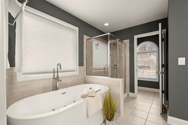 bathroom with a stall shower, tile patterned flooring, a bath, and baseboards