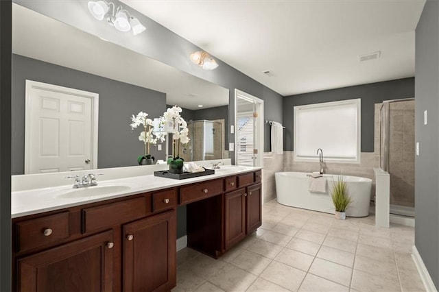 bathroom with tile patterned flooring, a soaking tub, tiled shower, and a sink