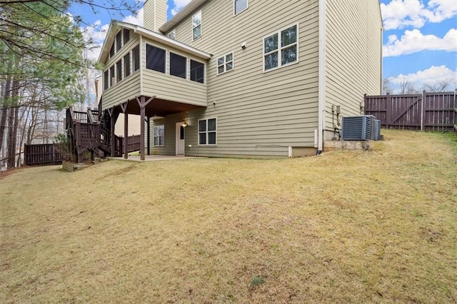 rear view of property with a gate, a sunroom, a chimney, and fence