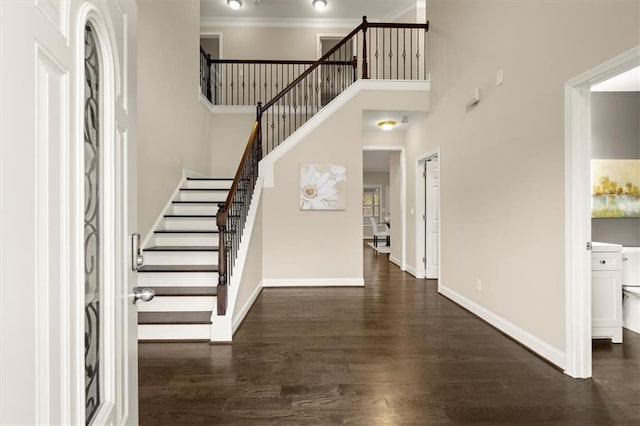 entrance foyer featuring dark wood-style flooring, a high ceiling, ornamental molding, baseboards, and stairs