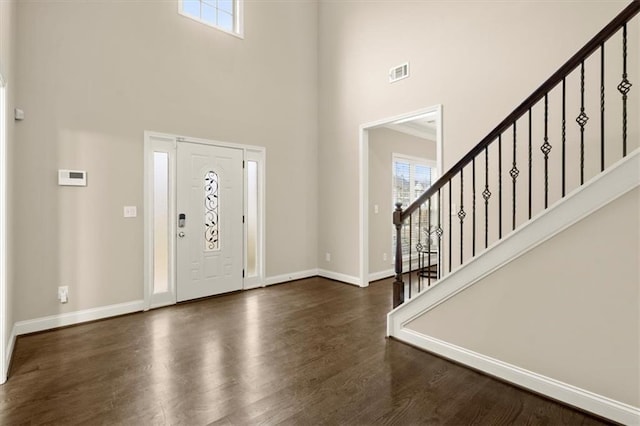 entryway with a towering ceiling, visible vents, baseboards, stairway, and dark wood-style floors