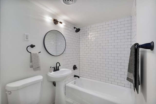 bathroom with toilet and tiled shower / bath combo