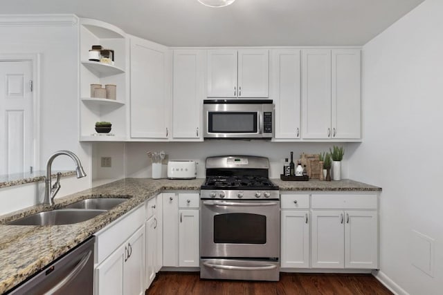 kitchen with sink, light stone countertops, white cabinets, and appliances with stainless steel finishes