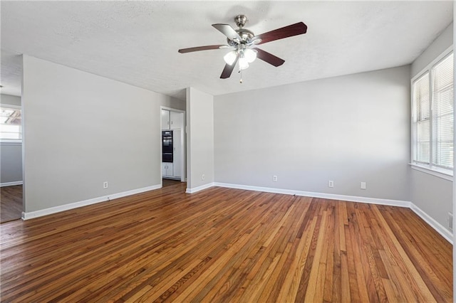 spare room with ceiling fan, a wealth of natural light, and hardwood / wood-style floors